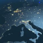 Mapa nocturno de Europa visto desde el espacio, mostrando luces urbanas y relieve terrestre iluminado, con tonos azules y grises. Representa la aplicación de la regulación NIS2.