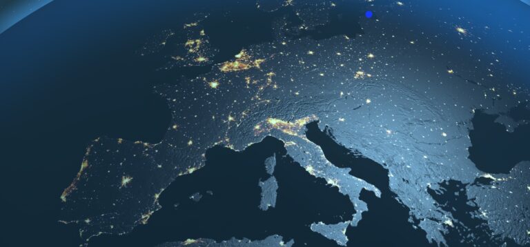 Mapa nocturno de Europa visto desde el espacio, mostrando luces urbanas y relieve terrestre iluminado, con tonos azules y grises. Representa la aplicación de la regulación NIS2.